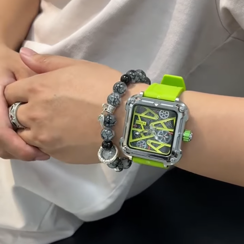 Person wearing a green watch with a detailed face and a beaded bracelet on a neutral background